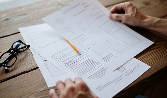 Крупный план: руки психолога и пациента с бланками психологических тестов на столе
